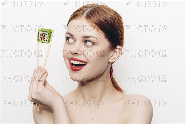 Caucasian woman holding sushi with chopsticks