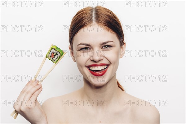 Caucasian woman holding sushi with chopsticks