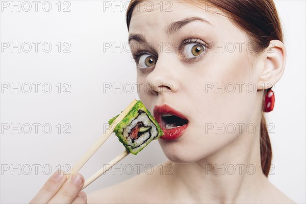 Caucasian woman eating sushi with chopsticks