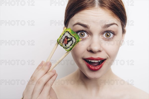 Caucasian woman holding sushi with chopsticks