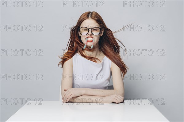 Caucasian woman sitting at windy table with candy in mouth