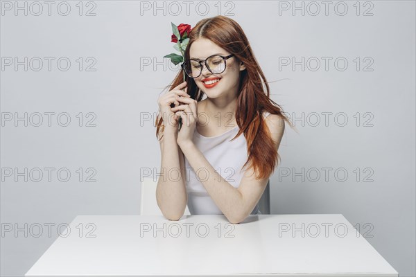 Caucasian woman sitting at windy table holding rose
