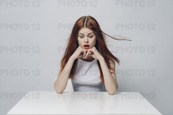 Surprised Caucasian woman sitting at windy table