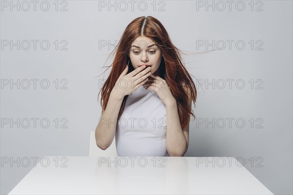 Surprised Caucasian woman sitting at windy table