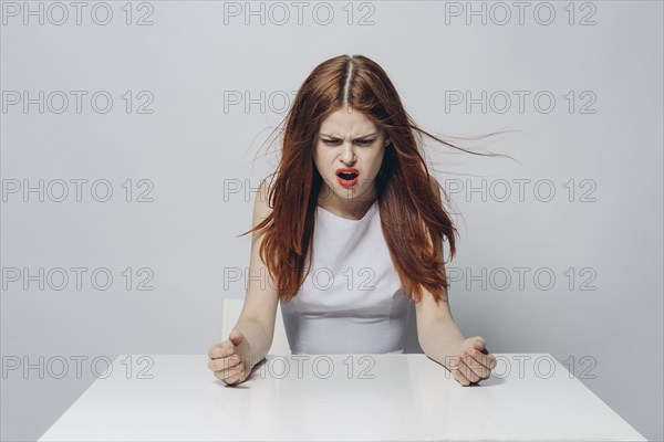 Angry Caucasian woman sitting at windy table