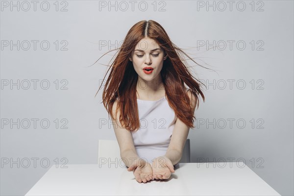 Hopeful Caucasian woman sitting at windy table