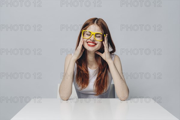 Laughing Caucasian woman sitting at table wearing yellow eyeglasses