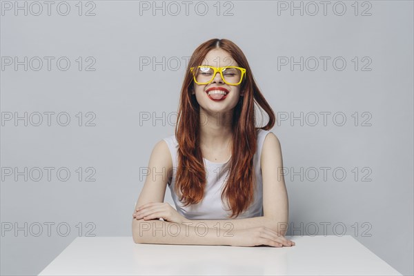 Caucasian woman sitting at table with tongue out