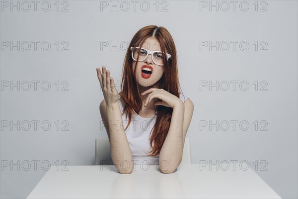 Caucasian woman with attitude sitting at table wearing white eyeglasses