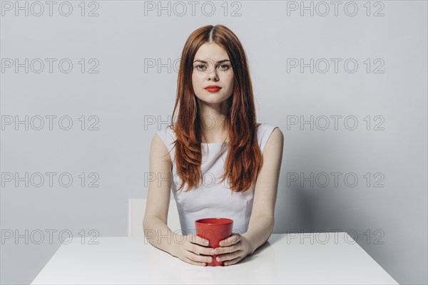 Caucasian woman sitting at table holding red cup