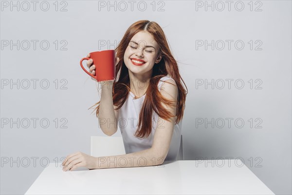 Caucasian woman sitting at windy table holding red cup