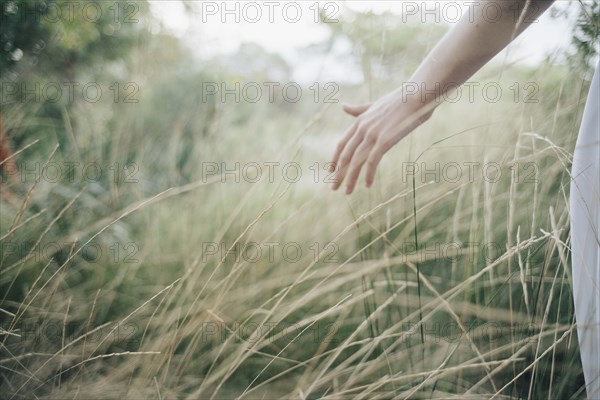 Hand of Caucasian woman standing in tall grass