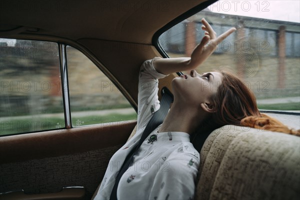 Caucasian woman in back seat of car looking up