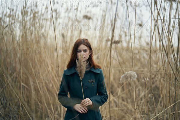 Caucasian woman standing in field holding stalk of grass