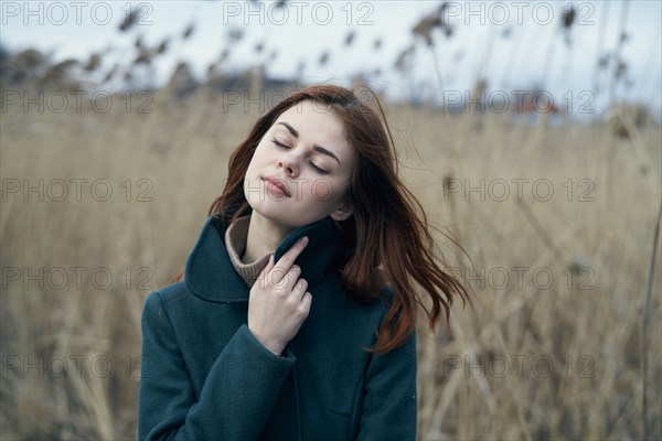 Pensive Caucasian woman standing in field holding collar