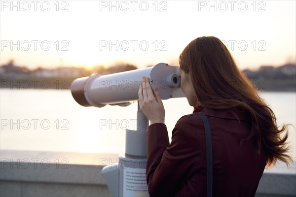 Caucasian woman using binoculars at waterfront