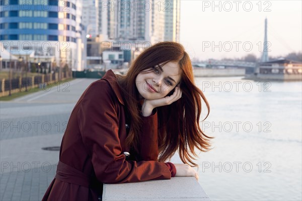 Smiling Caucasian woman leaning on wall at waterfront