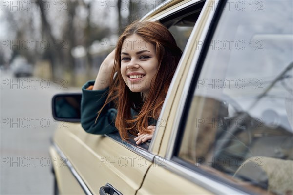 Smiling Caucasian woman leaning on car door