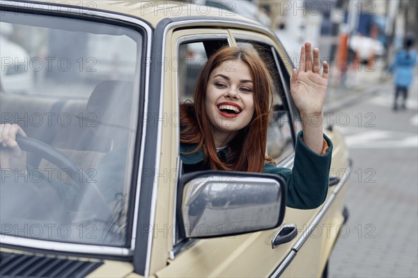 Smiling Caucasian woman driving car and waving