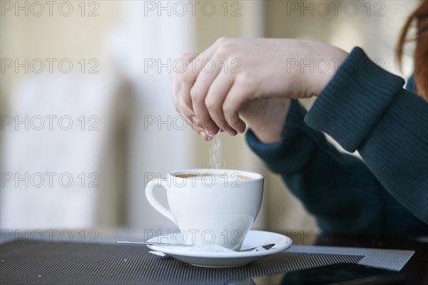 Caucasian woman pouring sugar into coffee
