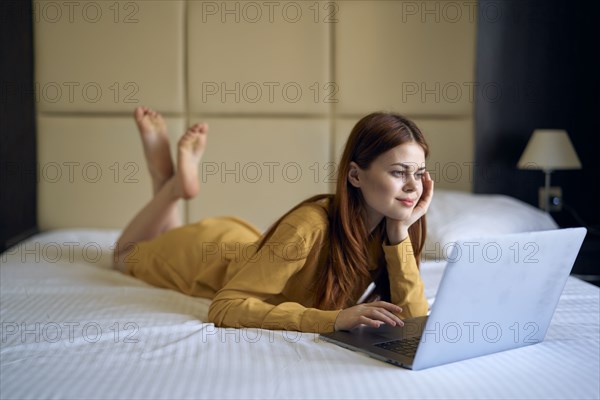 Caucasian woman laying on bed using laptop