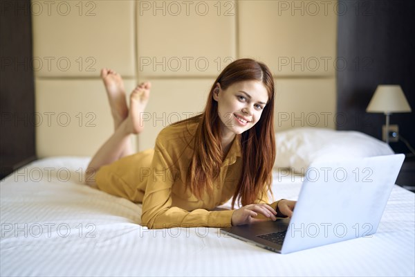 Caucasian woman laying on bed using laptop