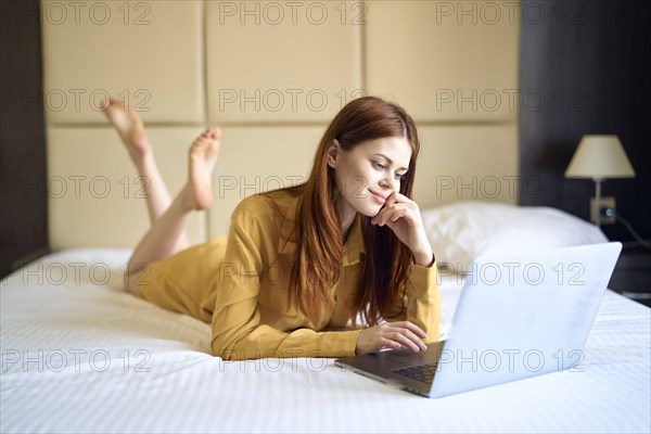 Caucasian woman laying on bed using laptop