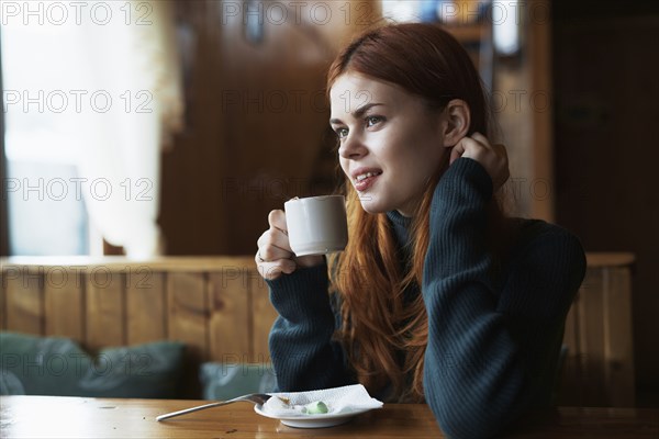 Smiling woman drinking coffee in cafe