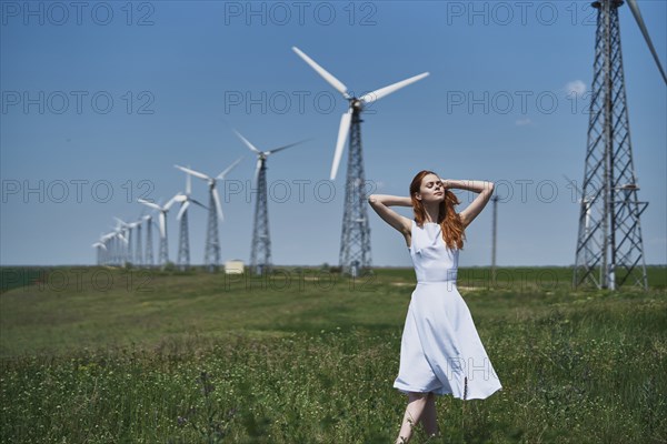 Caucasian woman in field near wind turbines