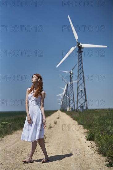 Caucasian woman on dirt path near wind turbines