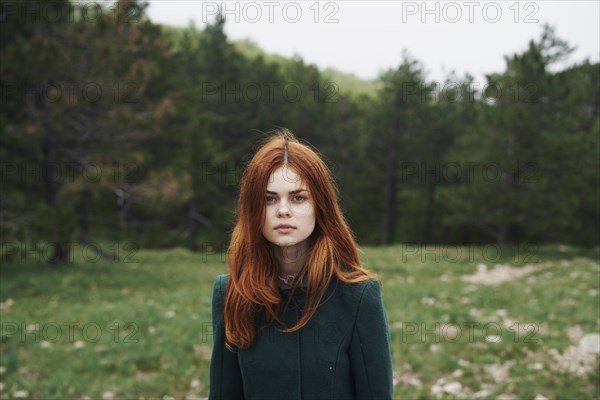 Serious Caucasian woman wearing coat in field