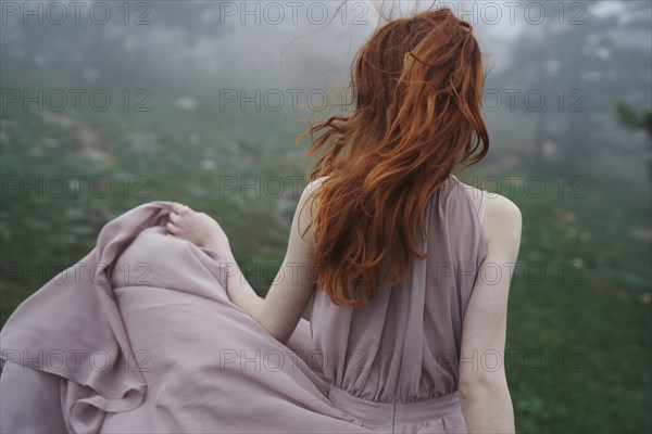 Wind blowing hair of Caucasian woman in field