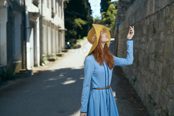 Smiling Caucasian woman wearing hat near stone wall