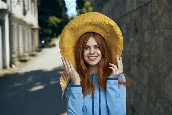 Smiling Caucasian woman wearing hat near stone wall