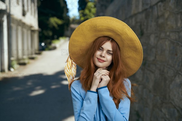 Smiling Caucasian woman wearing hat near stone wall