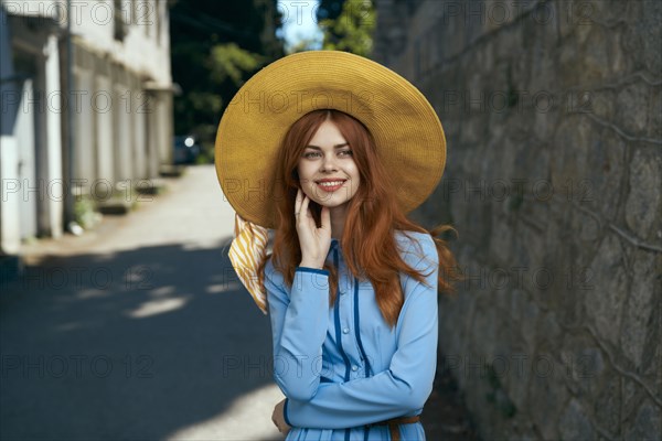 Smiling Caucasian woman wearing hat near stone wall