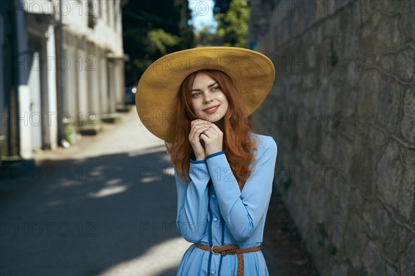 Pensive Caucasian woman wearing hat near stone wall