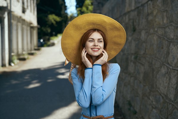 Smiling Caucasian woman wearing hat near stone wall