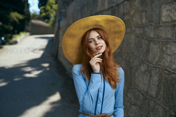 Smiling Caucasian woman wearing hat near stone wall