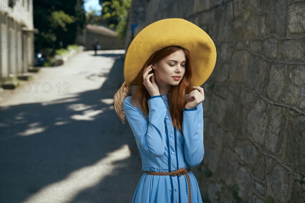 Pensive Caucasian woman wearing hat near stone wall