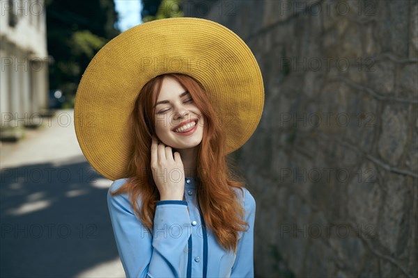 Laughing Caucasian woman wearing hat near stone wall