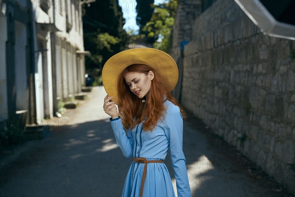 Smiling Caucasian woman wearing hat near stone wall