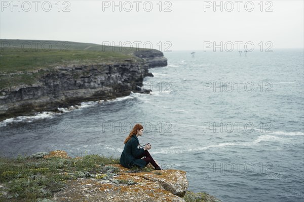 Caucasian woman examining camera near ocean