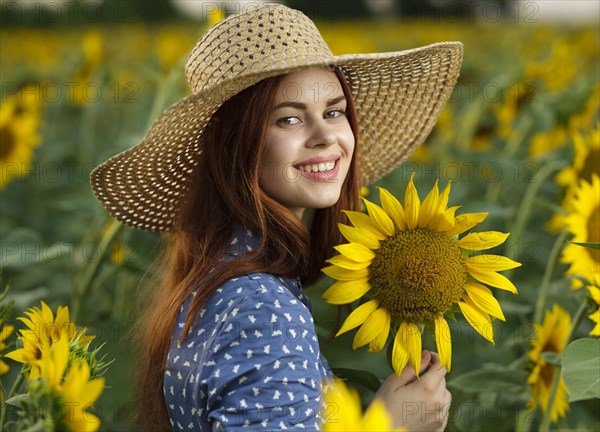 Smiling Caucasian woman wearing hat in field of sunflowers