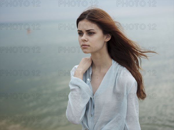 Pensive Caucasian woman standing near ocean