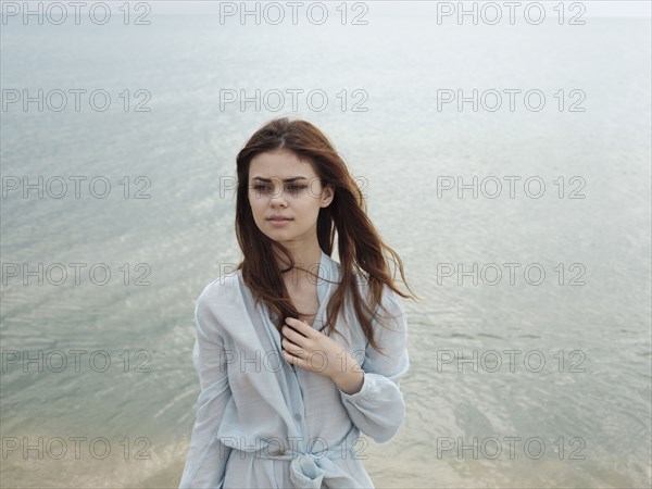 Serious Caucasian woman standing near ocean
