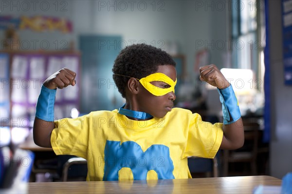 African American boy wearing superhero costume in classroom