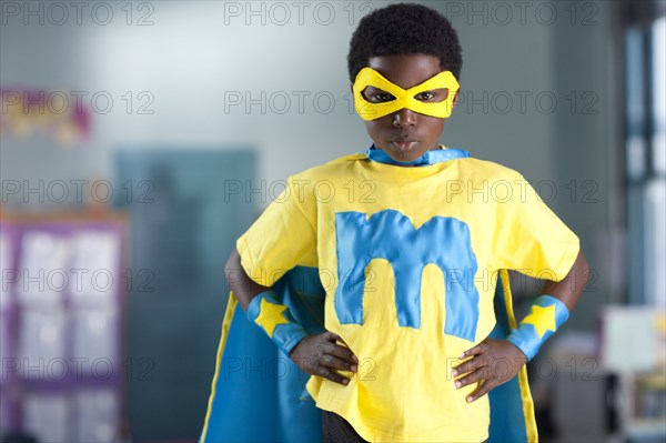 African American boy wearing superhero costume in classroom