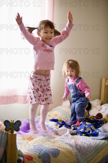 Two girls jumping on bed