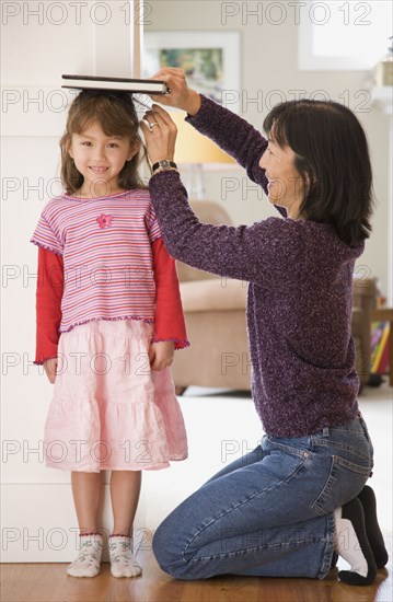 Mother measuring daughter's height